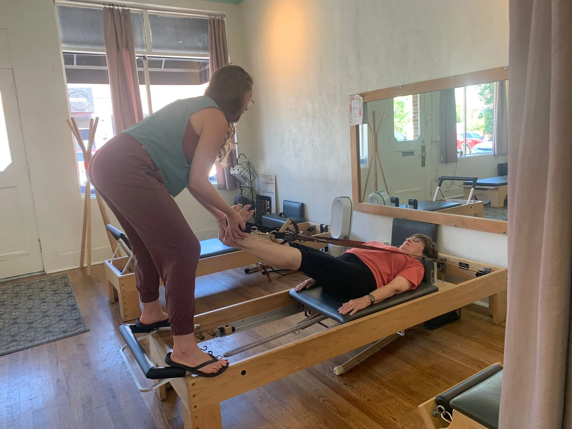 An instructor guides a client through a reformer exercise at Denver Pilates Movement